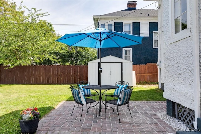 view of patio with a storage unit, a fenced backyard, outdoor dining area, and an outdoor structure