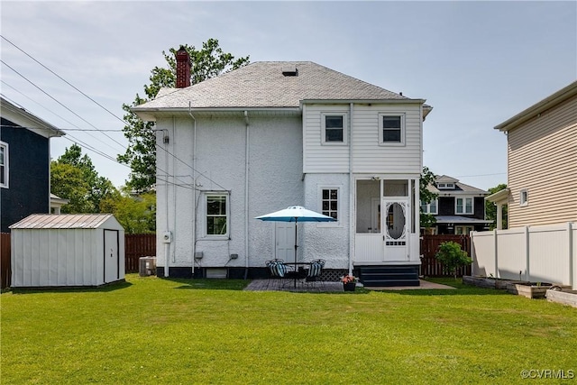 back of property with a lawn, fence, an outbuilding, and a shed