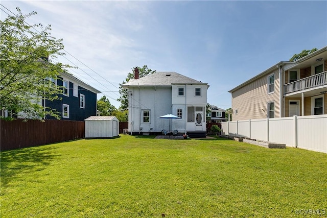 rear view of property featuring a yard, a fenced backyard, entry steps, and a storage unit