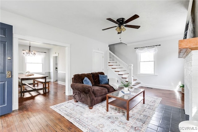 living room with hardwood / wood-style flooring, plenty of natural light, ceiling fan with notable chandelier, and stairs