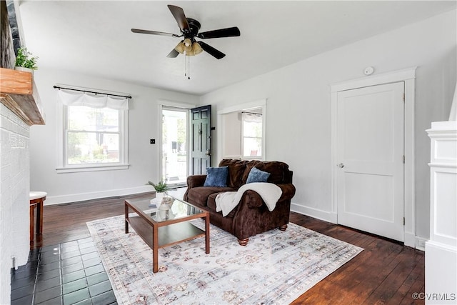 living room with baseboards, a ceiling fan, and dark wood-style flooring