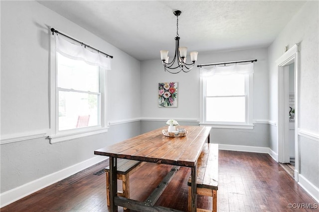 dining space featuring baseboards, a notable chandelier, and dark wood-type flooring