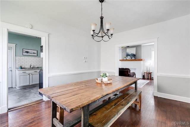 dining space featuring an inviting chandelier, dark wood finished floors, and baseboards