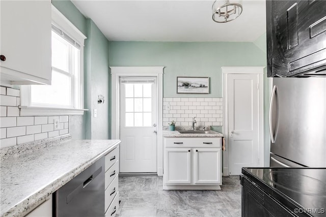 kitchen with backsplash, plenty of natural light, a sink, and dishwasher