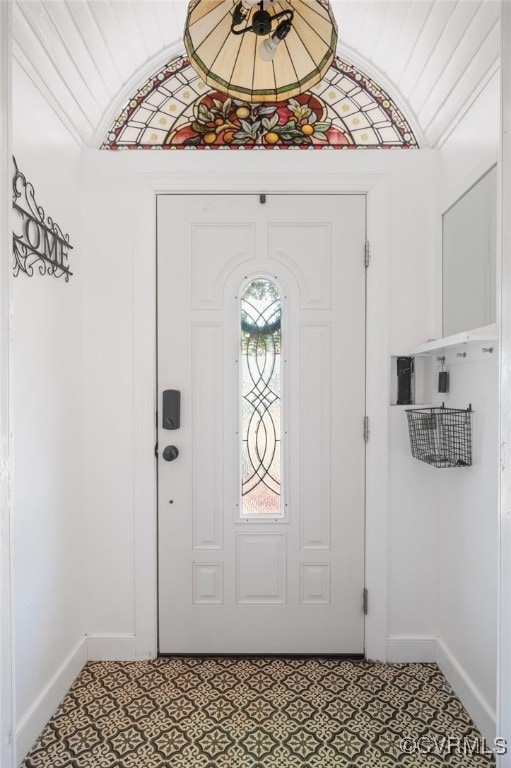 foyer featuring baseboards and vaulted ceiling