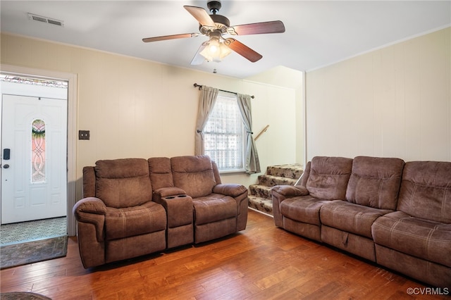 living area featuring crown molding, wood-type flooring, a ceiling fan, and visible vents