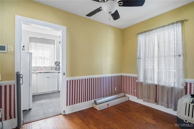 spare room with ceiling fan, wood finished floors, and a wainscoted wall