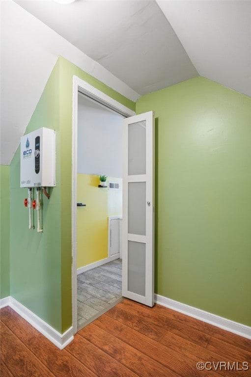 additional living space featuring baseboards, wood finished floors, and vaulted ceiling