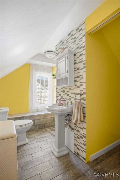 full bathroom with tile walls, tiled bath, toilet, and wood finished floors