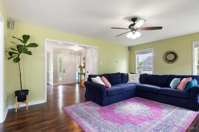 living area featuring baseboards, a ceiling fan, and dark wood finished floors
