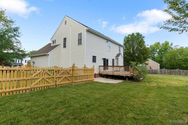 back of house with a fenced backyard, a deck, and a yard