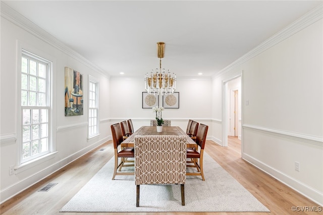 dining space with an inviting chandelier, crown molding, light wood-style flooring, and visible vents