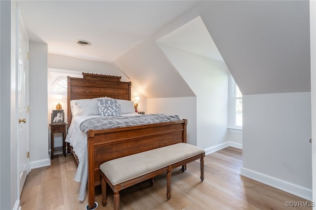 bedroom featuring baseboards, vaulted ceiling, multiple windows, and light wood finished floors
