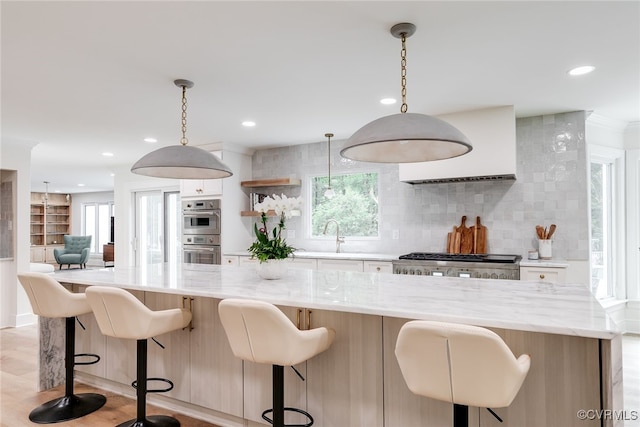 kitchen with double oven, tasteful backsplash, light stone counters, range, and a wealth of natural light
