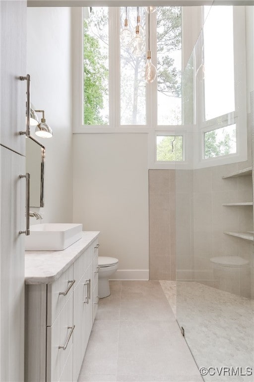 full bathroom featuring tile patterned flooring, walk in shower, toilet, and vanity