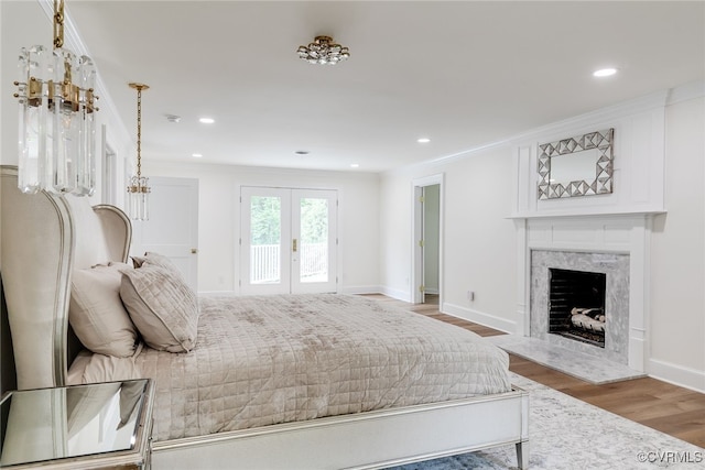 bedroom with access to outside, a premium fireplace, french doors, baseboards, and wood finished floors
