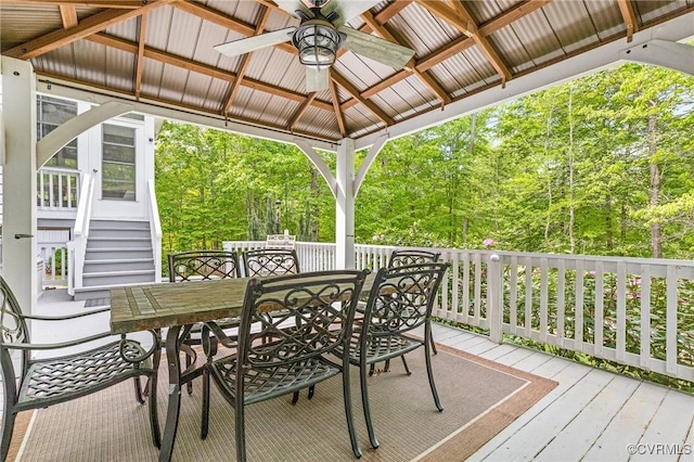 wooden terrace with a gazebo, a ceiling fan, and outdoor dining area