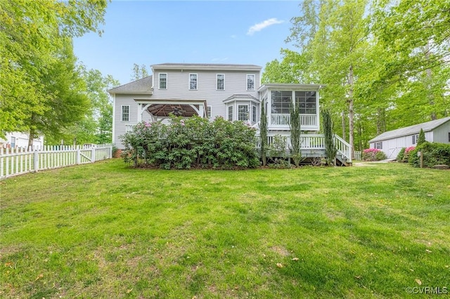 rear view of property with a sunroom, a lawn, and fence