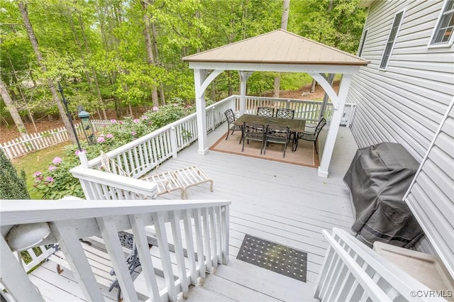 wooden deck with a gazebo, fence, and outdoor dining area