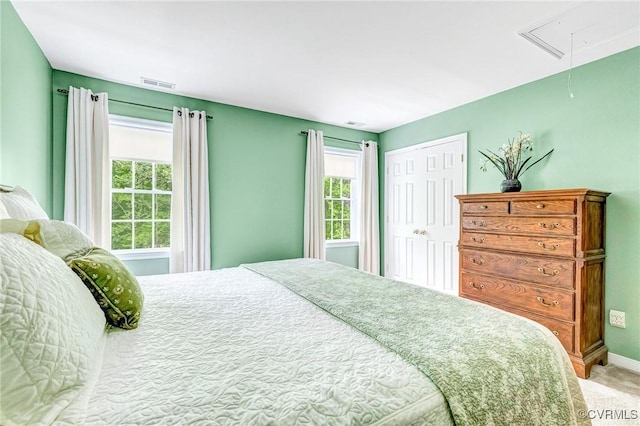 carpeted bedroom with visible vents, multiple windows, attic access, and a closet