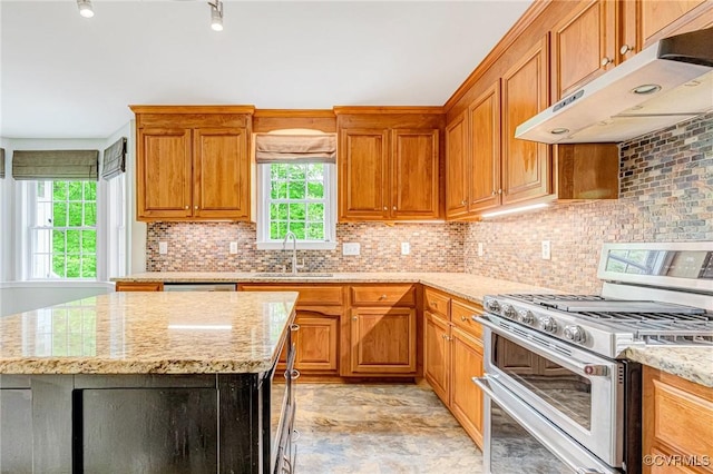 kitchen featuring light stone countertops, under cabinet range hood, a sink, backsplash, and double oven range