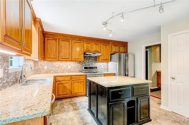 kitchen with a sink, appliances with stainless steel finishes, brown cabinetry, and under cabinet range hood