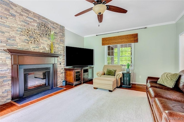 living room with crown molding, a ceiling fan, wood finished floors, and a fireplace