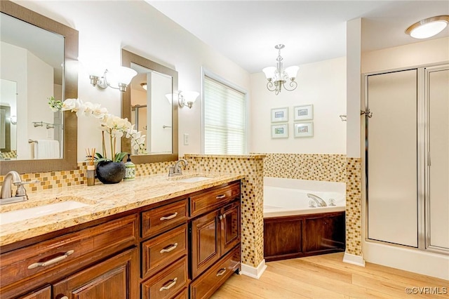 full bath featuring an inviting chandelier, a sink, wood finished floors, a bath, and a stall shower