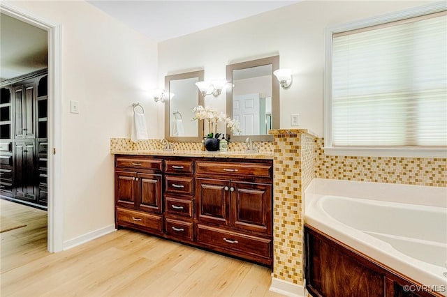 bathroom featuring double vanity, a sink, wood finished floors, and a garden tub