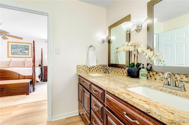 ensuite bathroom featuring backsplash, a sink, ensuite bathroom, and wood finished floors