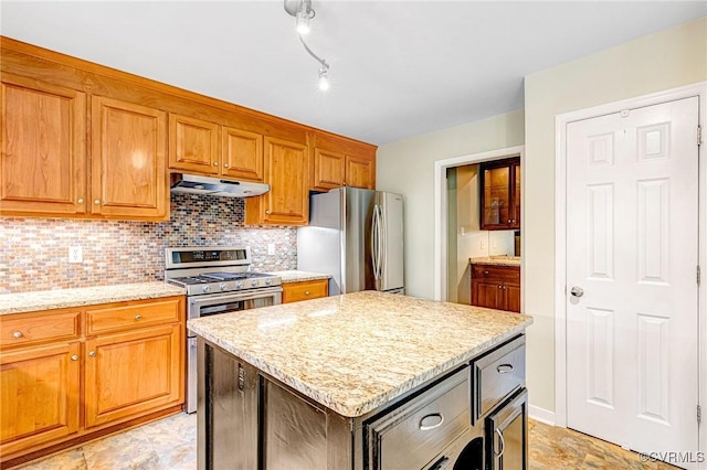 kitchen featuring decorative backsplash, appliances with stainless steel finishes, under cabinet range hood, and light stone countertops