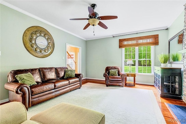 living area featuring crown molding, ceiling fan, baseboards, a fireplace with flush hearth, and wood finished floors