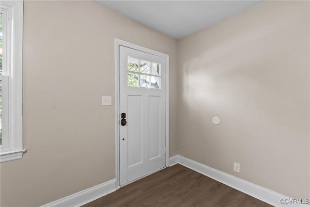 doorway to outside featuring baseboards and dark wood finished floors