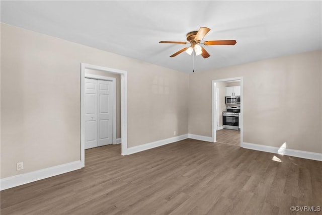 unfurnished room with baseboards, ceiling fan, and dark wood-style flooring