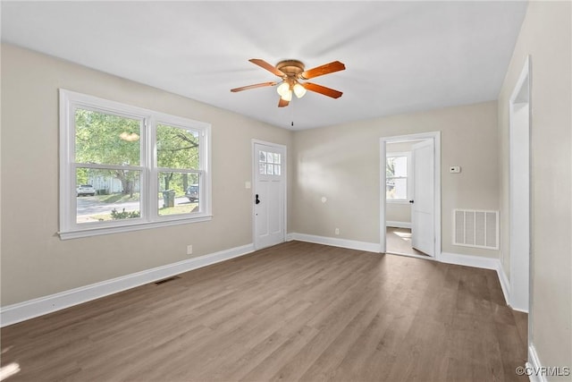 unfurnished room featuring visible vents, a ceiling fan, baseboards, and wood finished floors