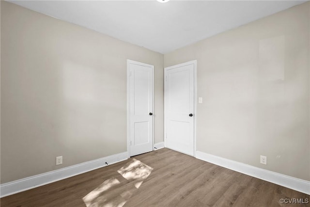 spare room featuring baseboards and wood finished floors