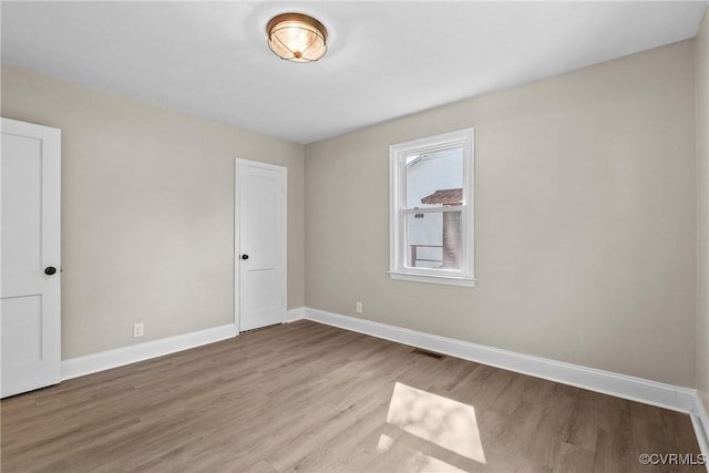 unfurnished room with baseboards, visible vents, and wood finished floors