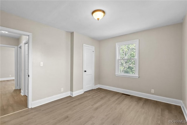 unfurnished bedroom with baseboards, wood finished floors, and visible vents