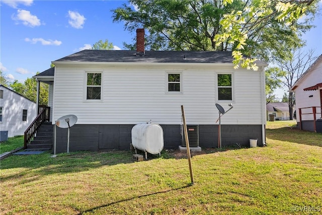 rear view of house featuring a chimney, heating fuel, a yard, and crawl space