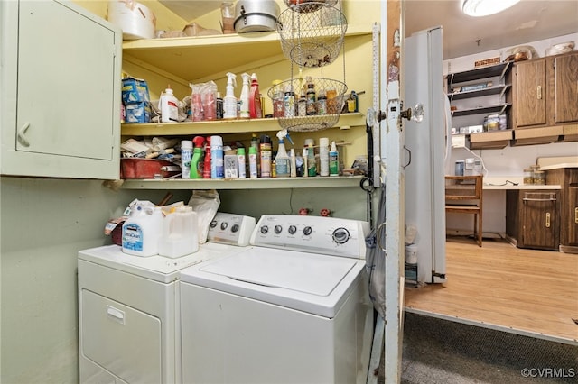 clothes washing area with cabinet space, independent washer and dryer, and wood finished floors