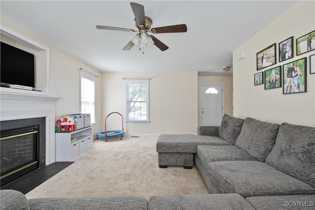 living room with a fireplace with flush hearth, baseboards, ceiling fan, and carpet flooring