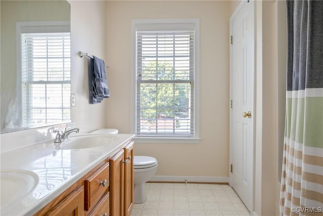 bathroom with a sink, tile patterned floors, toilet, and double vanity