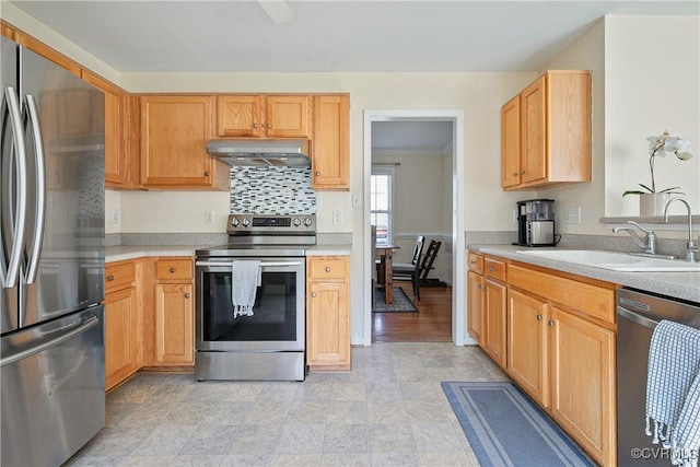 kitchen featuring light countertops, a sink, under cabinet range hood, and stainless steel appliances
