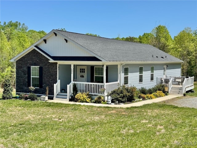 view of front of property featuring roof with shingles, a porch, and a front lawn