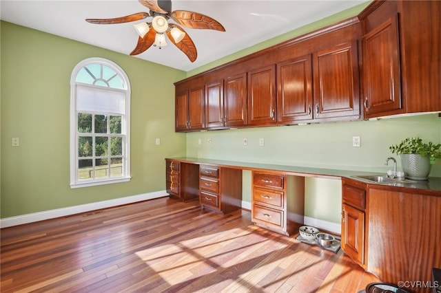 20145 Hunnicut Rd, Dinwiddie, VA 23803 - kitchen with a sink, baseboards, built in study area, light wood-type flooring, and a ceiling fan