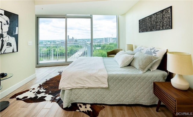 bedroom featuring access to outside, baseboards, and wood finished floors