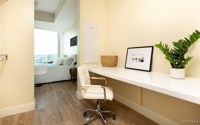 home office featuring baseboards, built in desk, and wood finished floors