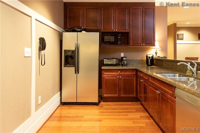 kitchen with black microwave, a sink, dishwasher, light wood-type flooring, and stainless steel refrigerator with ice dispenser