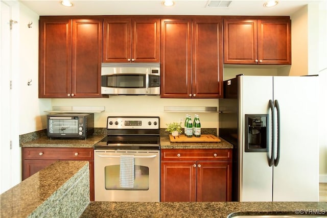 kitchen featuring reddish brown cabinets, recessed lighting, appliances with stainless steel finishes, and a toaster