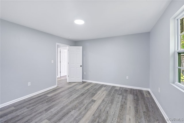 empty room featuring baseboards, wood finished floors, and a wealth of natural light